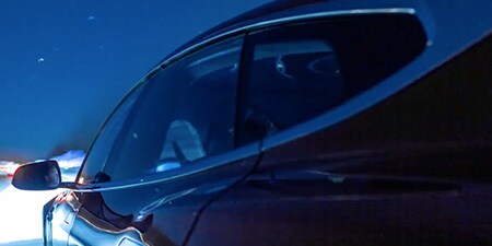 運転席側から捉えた夜に浮かぶセダン
