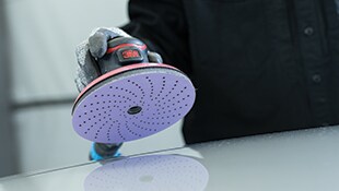 手袋を着用した作業者がクリーンサンディングディスクを装着した３Ｍ™ ダブルアクション サンダー を平滑な面に当てている様子
