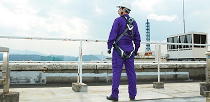 A man wearing a safety helmet, jumpsuit, and a fall protection harness
