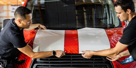 IJ280をボンネットに施工する2人の施工者
