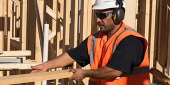 安全眼鏡、安全帽、安全ベスト、聴覚保護具を着用した建設現場作業員

