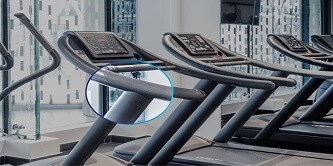 3 台のトレッドミルが並んだジムで、手すりとベースの交差部分が強調表示されています。強調表示された領域が拡大されています。
