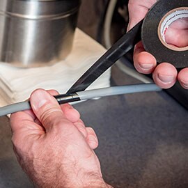 man using electrical tape on cable