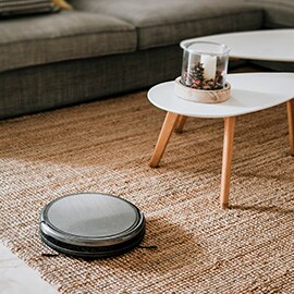 リビングルームのカーペットを掃除しているワイヤレスのロボット掃除機。