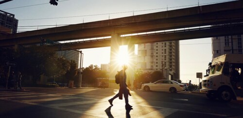 夕日が沈む頃に横断歩道を渡る人の遠景
