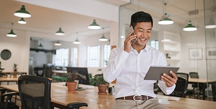 Asian businessman talking on his cellphone and holding his tablet.
