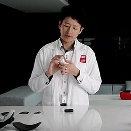 Man in a lab coat holding a manufactured component.