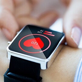A smart watch on a person's wrist with a heart sensor on.