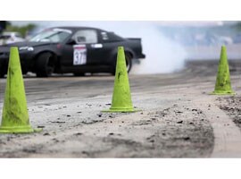 Video still of a car driving past boundary cones on a racetrack