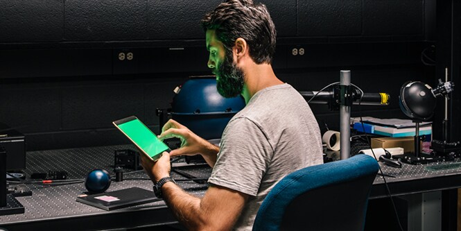 Man holding a tablet with a green screen on it.
