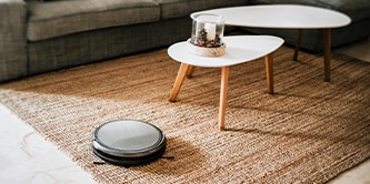 モダンなコーヒーテーブルとハンズフリー掃除機がある、カーペット敷きのリビングルーム。
