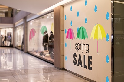 Wall wrap on exterior of retail store with umbrellas and words “spring sale.”