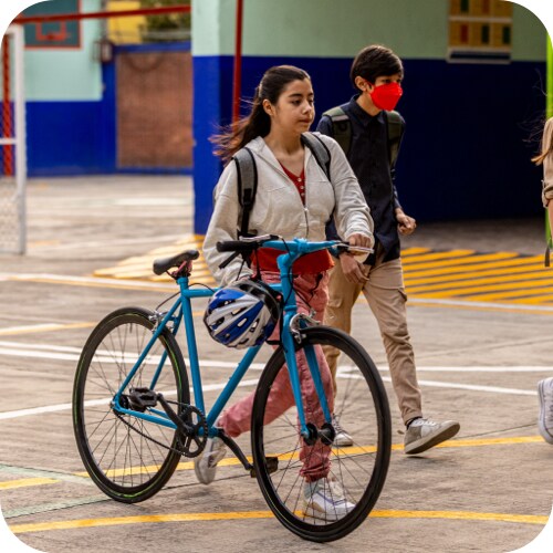 学校の敷地内で自転車を押して歩く少女
