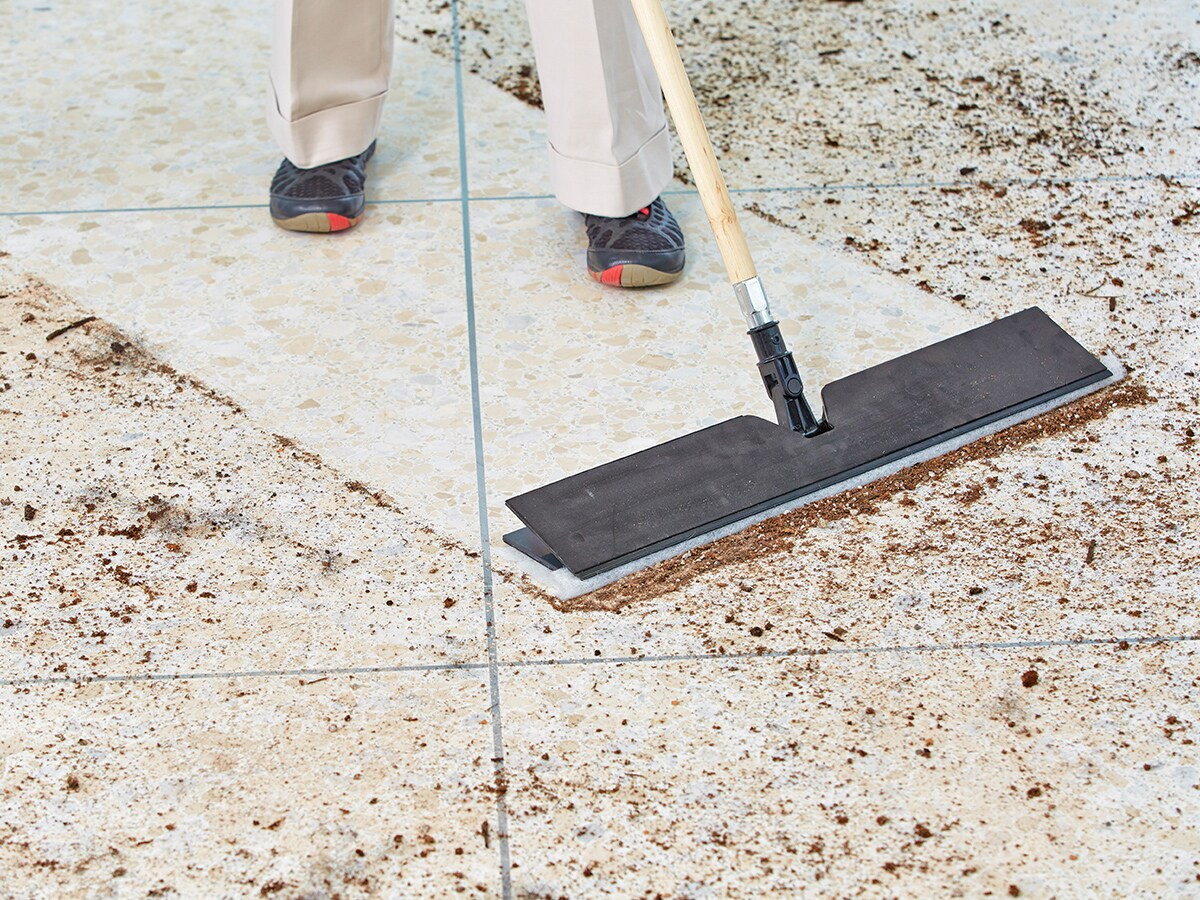 A worker using a buffer to treat a shiny floor.
