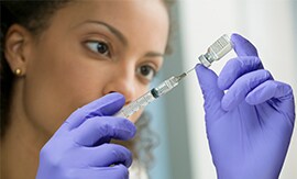 注射器でバイアルから液体を採取する女性科学者
