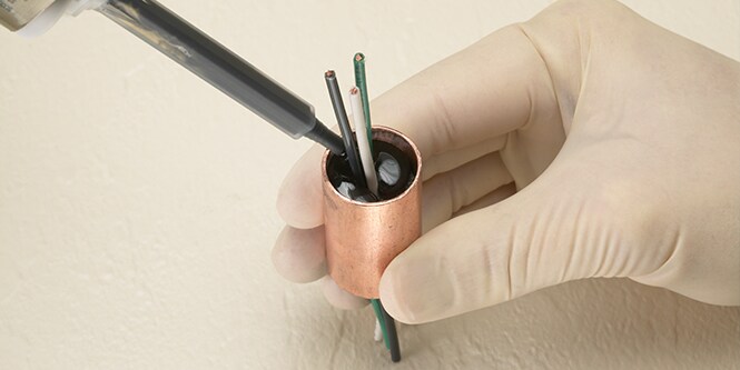 手作業での接着剤の塗布による電気コードの封止
