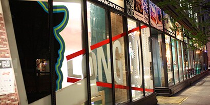 夜間の店頭からは、明るい店内とグラフィックスが施されたウィンドウが見えます。
