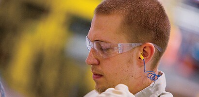 A man wearing eye protection and safety earplugs
