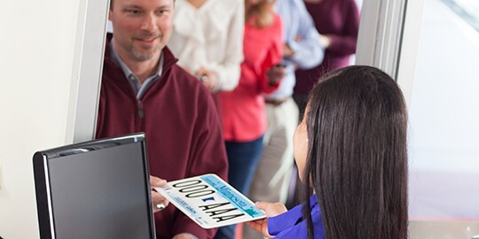 お客様にナンバープレートを手渡すDMV職員
