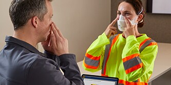 A man directing how to wear a respirator correctly

