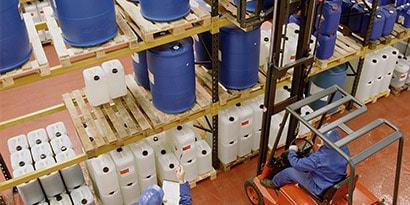 化学溶剤の保管所で、化学薬品の巨大なプラスチック容器の在庫を確認している作業者。
