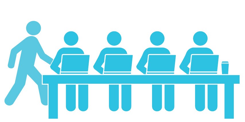 People talking at a desk with a computer monitor
