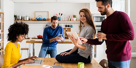 People using consumer electronics in an office including a laptop, phones, and tablets.
