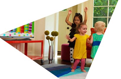  An image of a children dancing in a living room in front of a large flat screen television.