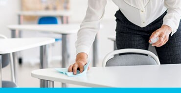 school teacher disinfecting desks in the classroom.