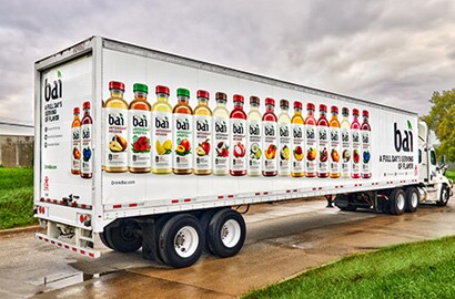 Semi-truck with fleet vehicle wrap with images of bottles of juice.