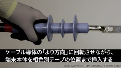 ケーブル設置用のスパイラルツールを持つ手袋をした手、安全性と精度を強調しています。
