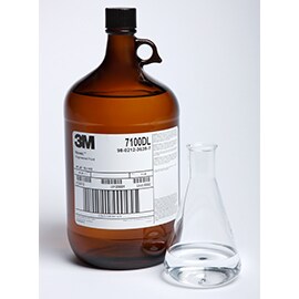 ３M™ Novec™高機能性液体の琥珀色の1ガロン入りガラスボトルと、Novec™ 7100高機能性液体の入った透明のビーカー。