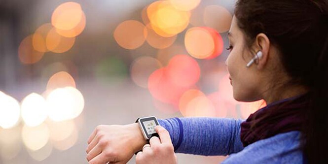 運動しながらスマートウォッチを使っている女性。
