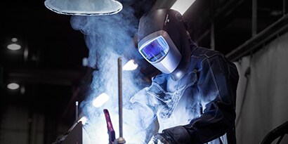 Image of a person wearing a welding mask and safety gear while working on a welding project
