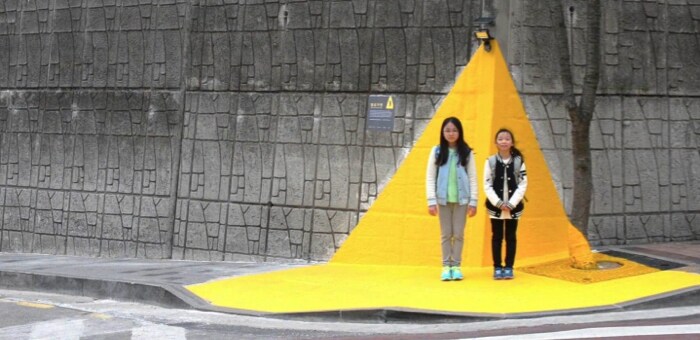 韓国で「イエローカーペット」の上に立って横断歩道の信号待ちをしている2人の少女。
