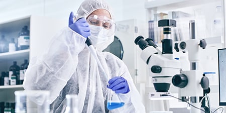 Female scientist pippetting liquid to a flask in lab

