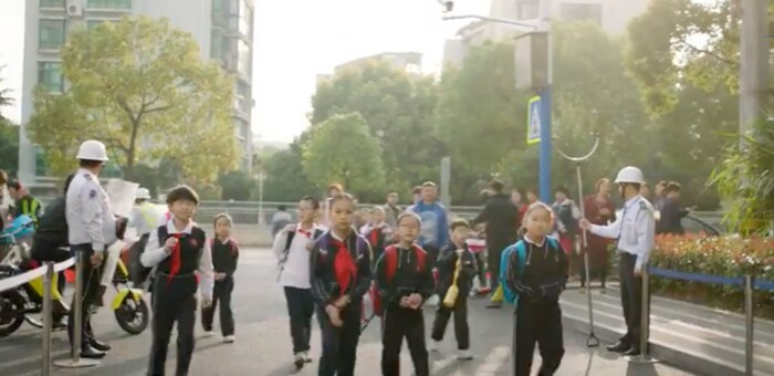 学校巡回ボランティアの協力を得て道路を横断する中国の小学生たち

