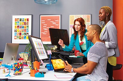 Three people looking at a desktop computer's screen.