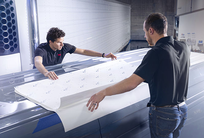 車両の屋根に 3M™ クーリングフィルムを施工する技術者
