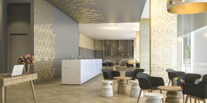 Lobby with comfortable chairs and tables, with walls that have graphic wraps and long desk with architectural finishes.
