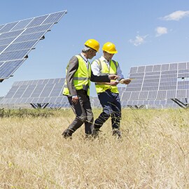 Two men walking next to solar panels producing solar 