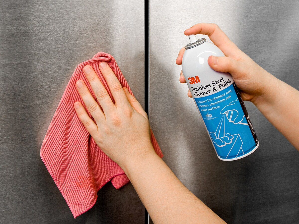 A kitchen worker using 3M scrubber to clean stainless steel pot.
